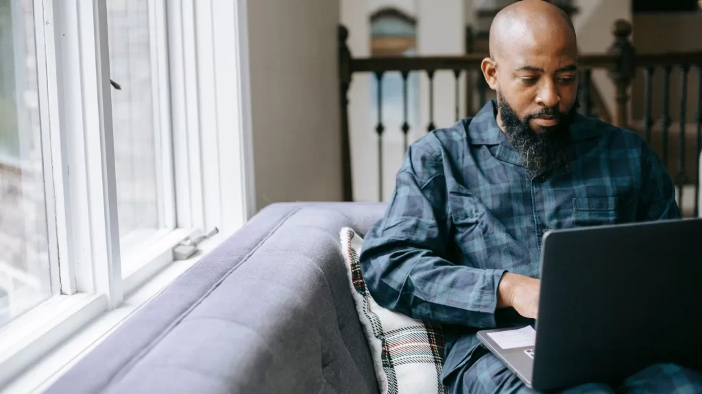 A bald, African-American man is looking at his laptop intently