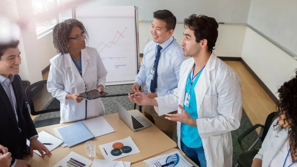 A group of doctors and marketing professionals are laughing while discussing something about B2B marketing in the healthcare industry.