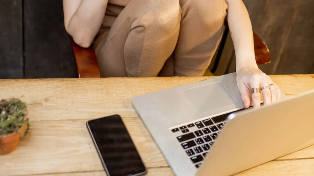 Someone working with their laptop open in a wooden table