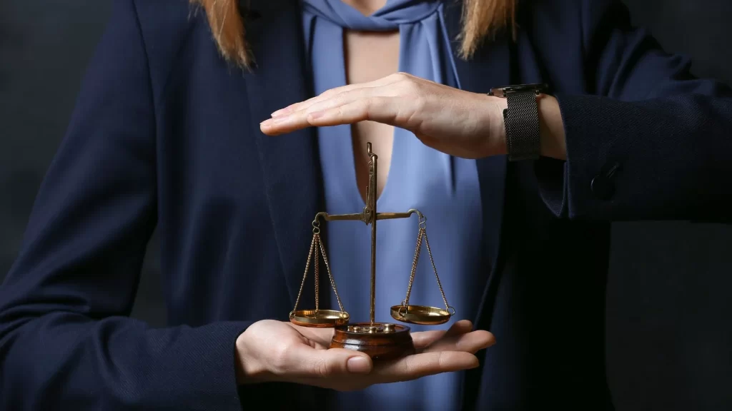 A woman holding a small justice scale between her hands