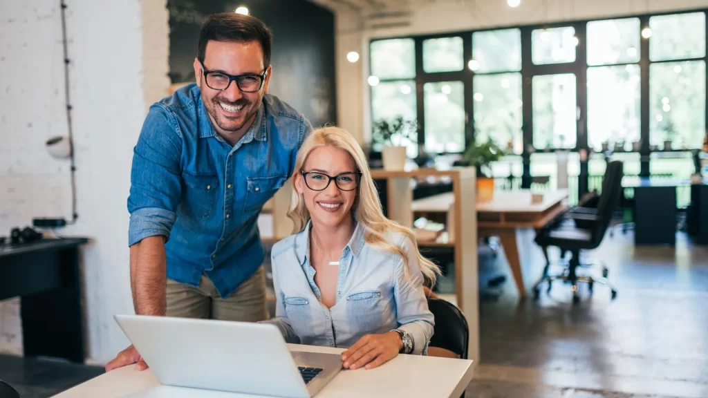 Male and female business owners smiling while looking at the performance of their chosen local SEO service provider