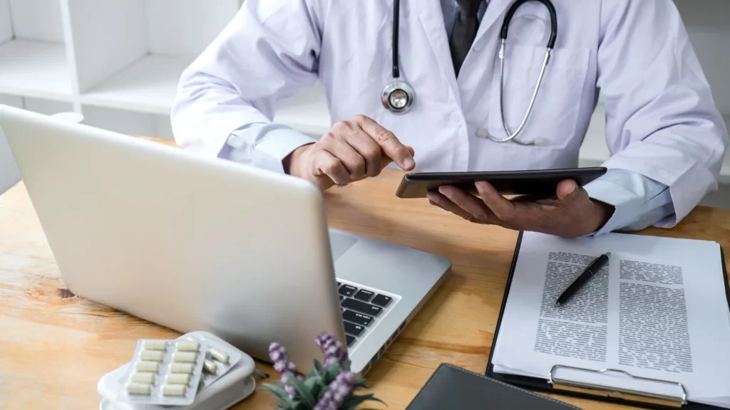 The profile of a doctor seems to be working on healthcare content marketing with both a laptop and a tablet open.